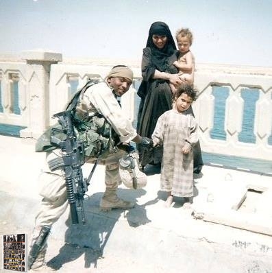 Vrail George in the Army posing with Iraqi families